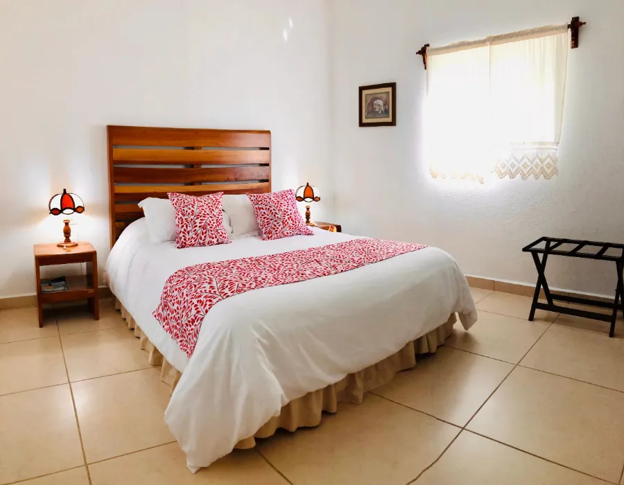Habitación con cama matrimonial y camino de cama rojo