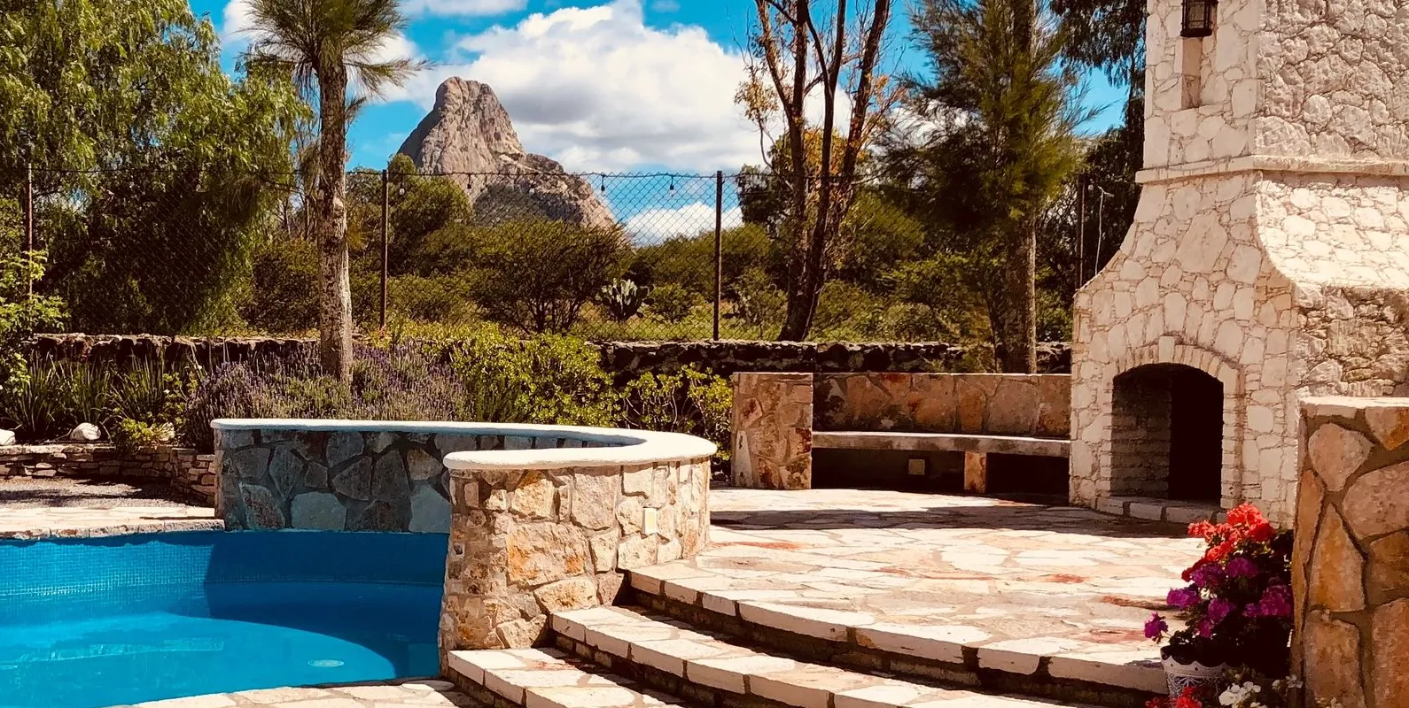 La alberca del jardín con la Peña de Bernal al fondo, entre árboles